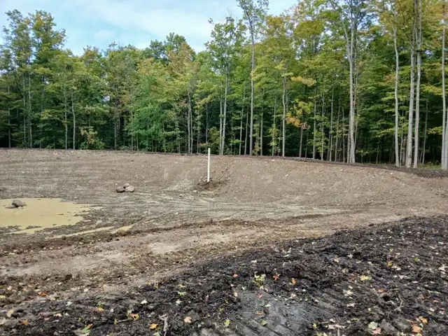 Cleared lot with stripped topsoil and surface water pooled after grading